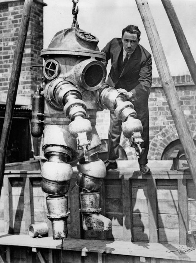 Mr. J.S. Peress, the inventor of the new armoured diving suit, getting his device ready for tests in the tank today at Weybridge. United Kingdom. May 28, 1930.